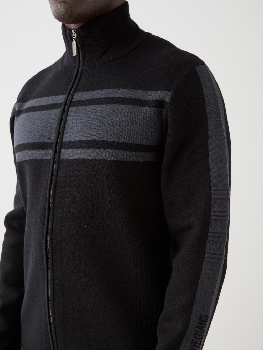 We Norwegians | FW25 | Mens Rocky Full ZipUp_Black | Model wearing this fine knitted sweater with a 2-way front zipper opening, designed in a retro style with subtle color blocks on the chest and sleeves | Shot against an off-white background | Close-up