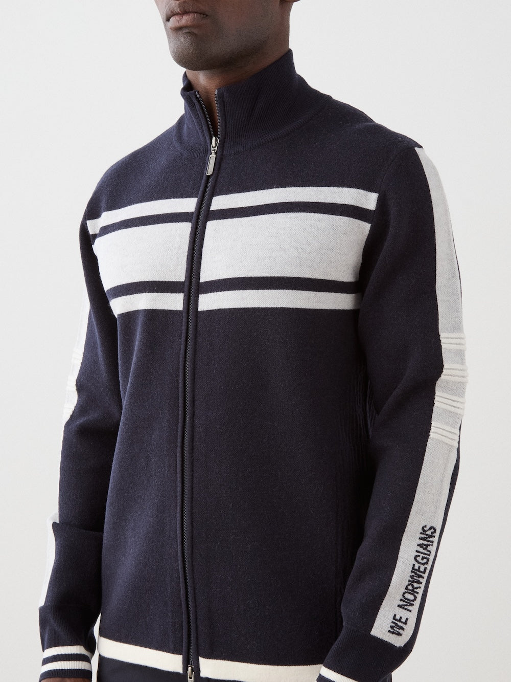 We Norwegians | FW25 | Mens Rocky Full ZipUp_Navy blue | Model wearing this fine knitted sweater with a 2-way front zipper opening, designed in a retro style with contrasting color blocks on the chest and sleeves | Shot against an off-white background | Close-up