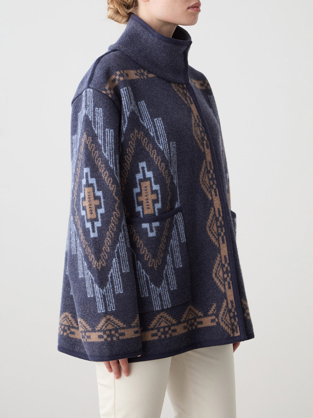 We Norwegians_FW25_Womens | Model is wearing the Navy blue Kautokeino jacket with Off white Tyin Bootleg Ski pants | The jacket come with a jacquard pattern inspired by Native and Indigenous American art | Photograph showing pattern details of the garment against a white background