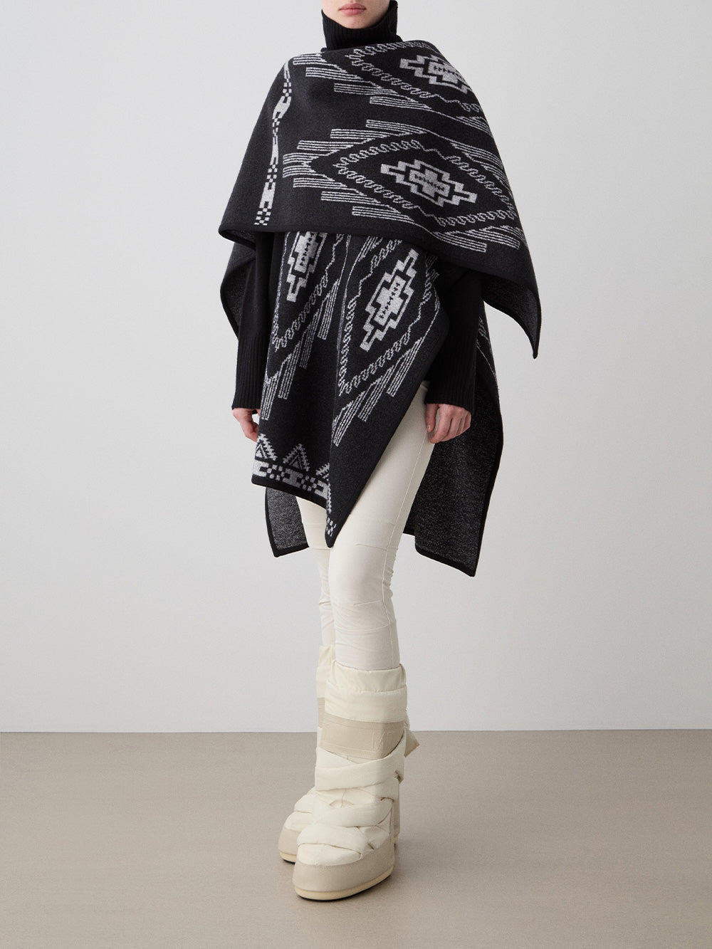 We Norwegians_FW25_Model is wearing the Kautokeino poncho | Black in color with a jacquard pattern inspired by Native and Indigenous American art | Made with boiled merino wool | Photograph showing the fall and drape features of the garment