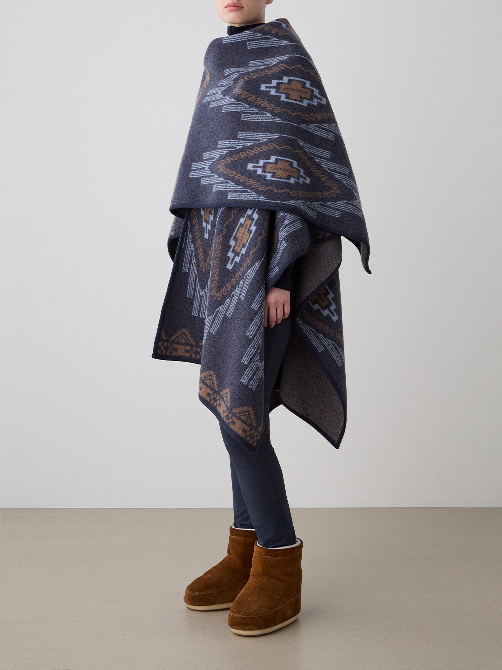 We Norwegians_FW25_Model is wearing the Kautokeino poncho | Navy Blue in color with a jacquard pattern inspired by Native and Indigenous American art | Made with boiled merino wool | Photograph is showing the fall and drape features of the garment