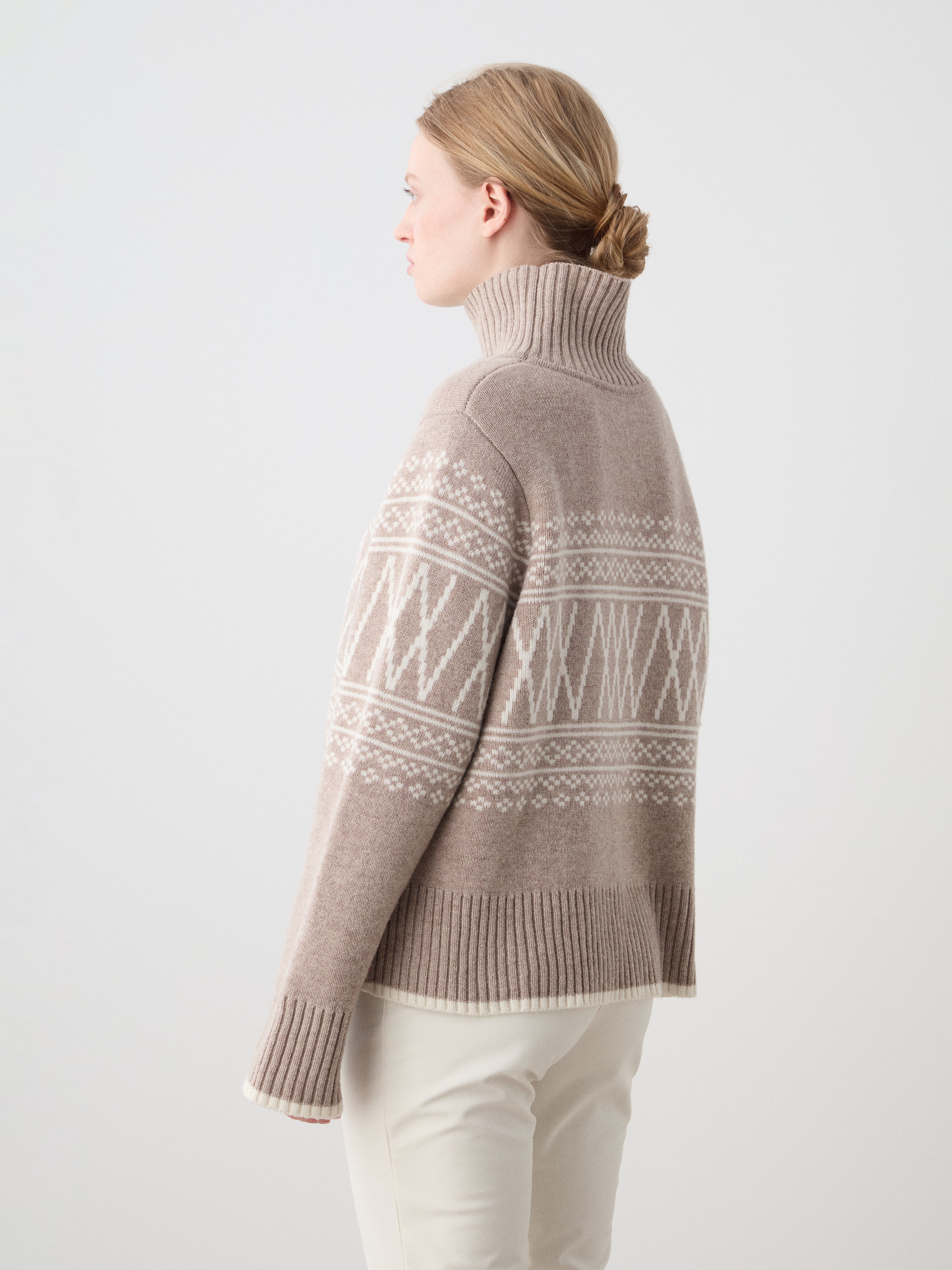 Woman wearing a patterned turtleneck sweater on a white background