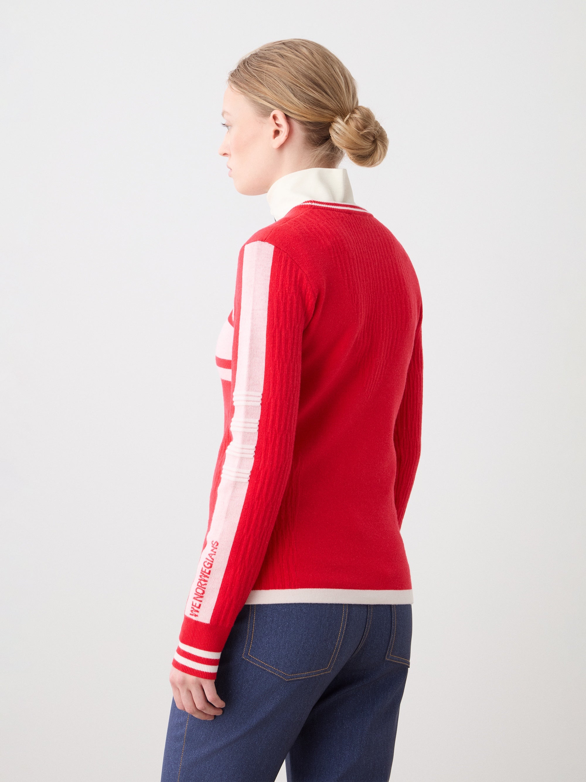 We Norwegians | FW25 | Womens Rocky Ski Sweater_Red | Model wearing this mid-weight knit designed in a retro style with a round neckline and contrasting color block panels on the chest and sleeves - paired with the Western ski pants | Shot against an off-white background | Back