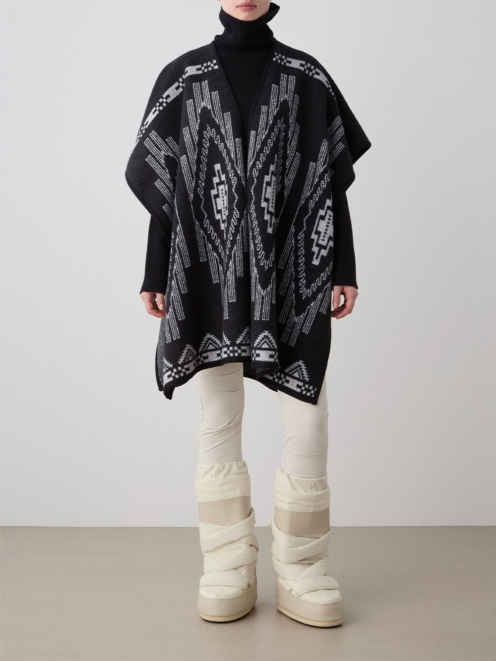 We Norwegians_FW25_Model is wearing the Kautokeino poncho | Black in color with a jacquard pattern inspired by Native and Indigenous American art | Made with boiled merino wool | Front view