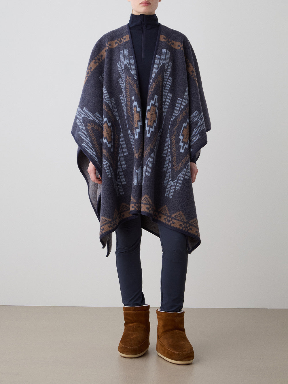 We Norwegians_FW25_Model is wearing the Kautokeino poncho | Navy Blue in color with a jacquard pattern inspired by Native and Indigenous American art | Made with boiled merino wool | Front view