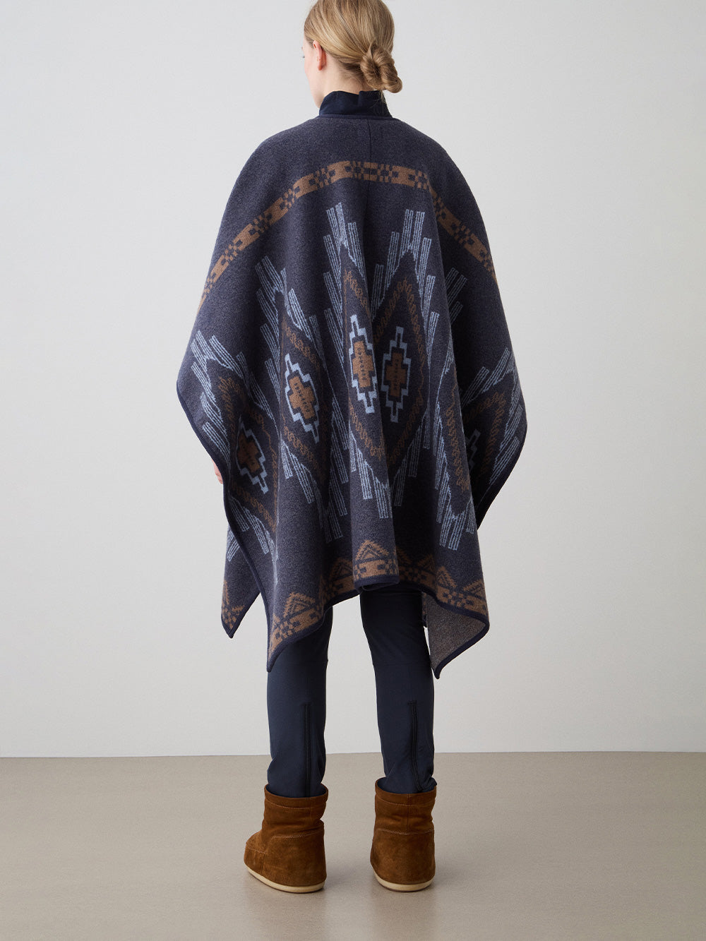 We Norwegians_FW25_Model is wearing the Kautokeino poncho | Navy Blue in color with a jacquard pattern inspired by Native and Indigenous American art | Made with boiled merino wool | Back view