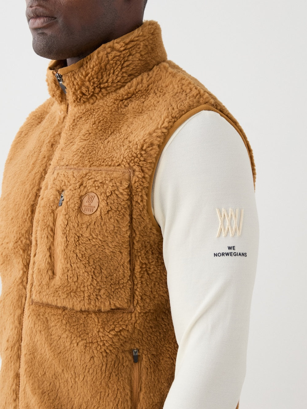 We Norwegians | FW25 | Mens Kebnekaise Vest_Cinnamon | Model wearing this fleece vest with front zipper opening, zipped chest pocket and side pockets - over an off-white top | Shot against an off-white background | Close-up