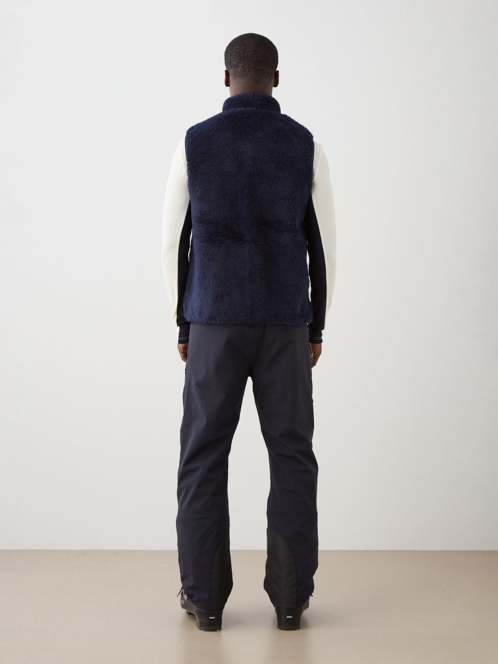 We Norwegians | FW25 | Mens Kebnekaise Vest_Navy blue | Model wearing this fleece vest with front zipper opening, zipped chest pocket and side pockets -over an off-white top - paired with black ski pants | Shot against an off-white background | Back