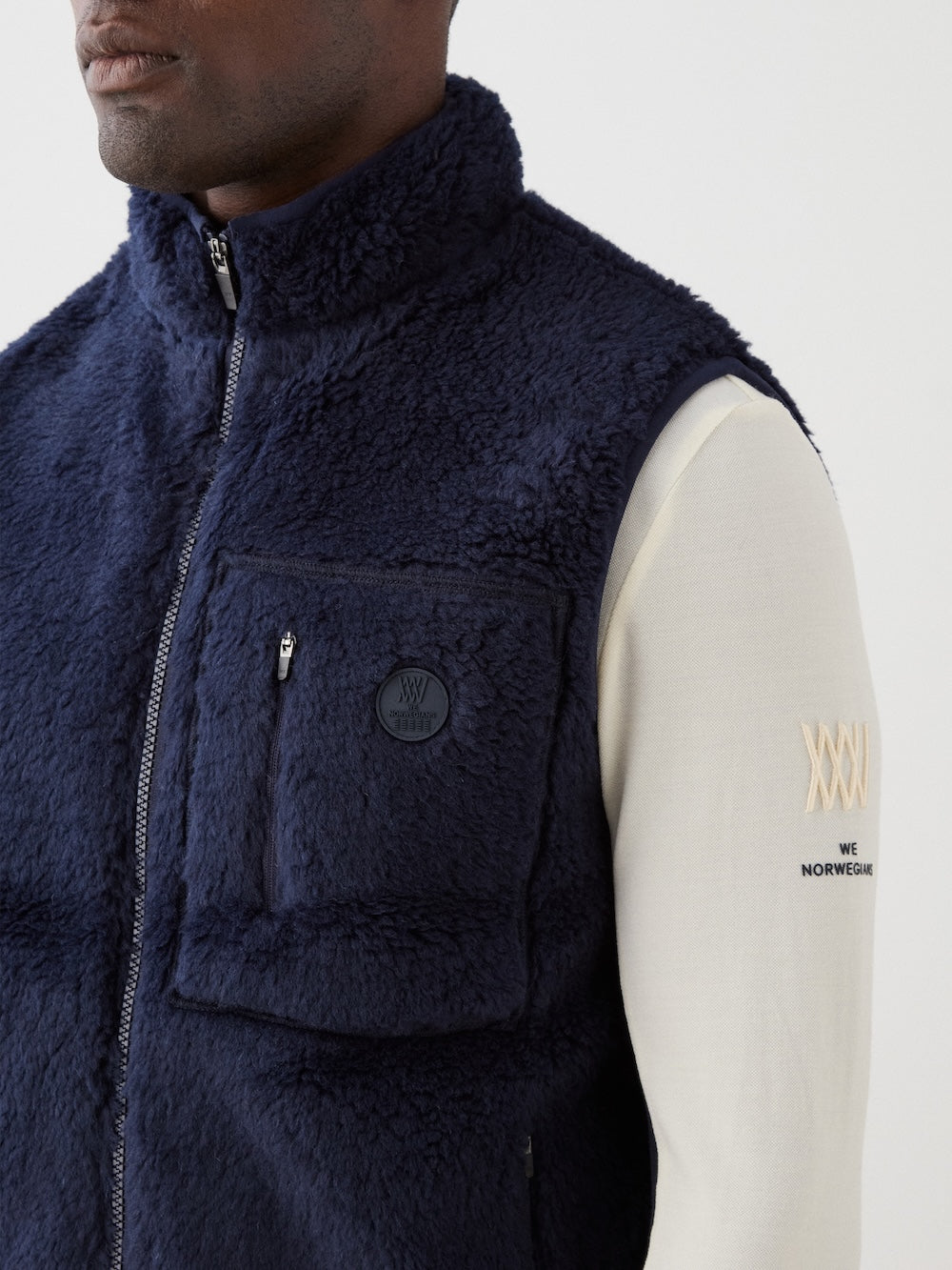 We Norwegians | FW25 | Mens Kebnekaise Vest_Navy blue | Model wearing this fleece vest with front zipper opening, zipped chest pocket and side pockets -over an off-white top | Shot against an off-white background | Close-up