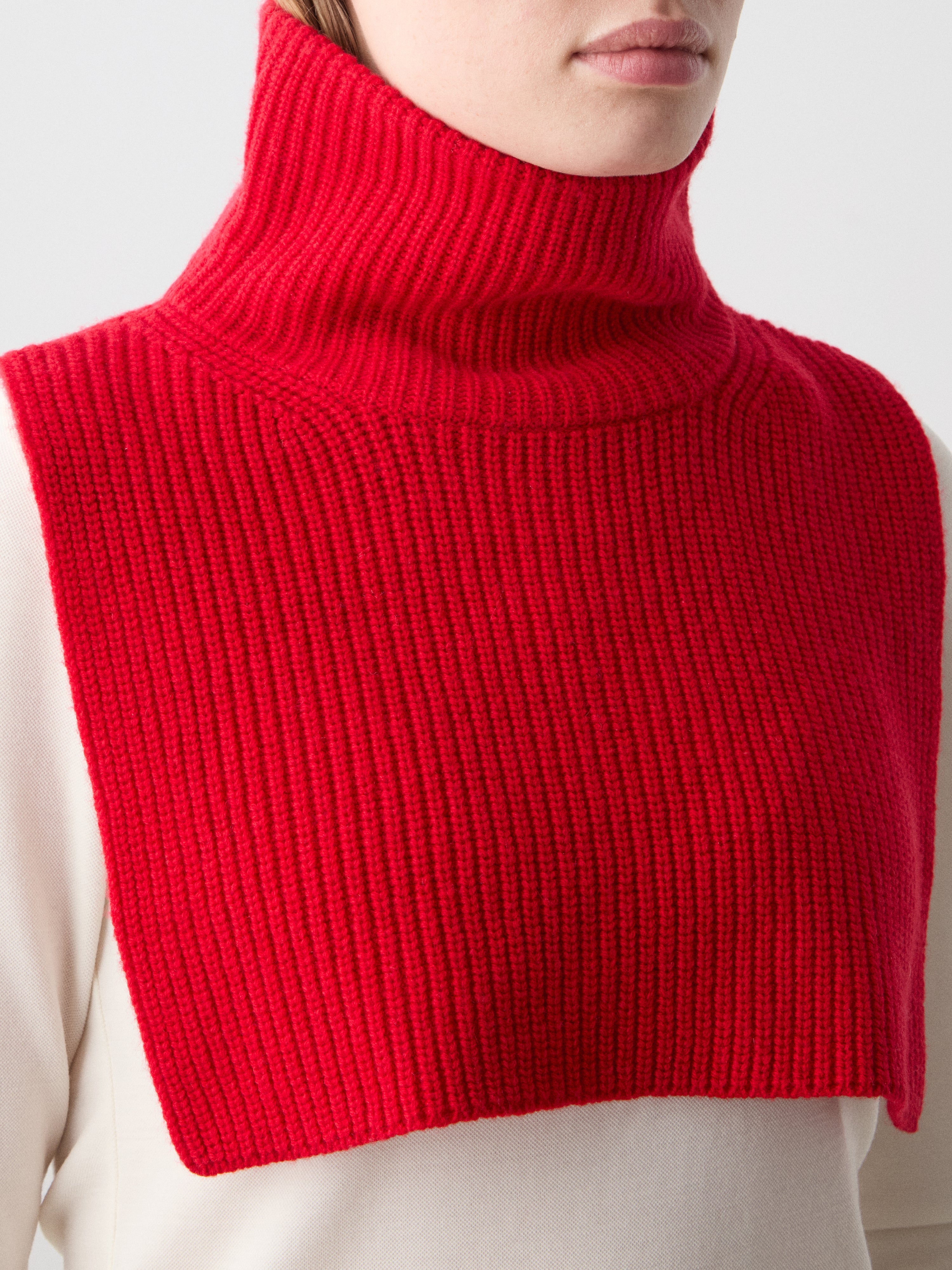 We Norwegians | FW25 | Dal Bib_Red | Model wearing the knitted turtle neck bib over a white sweater | Shot against an off-white background