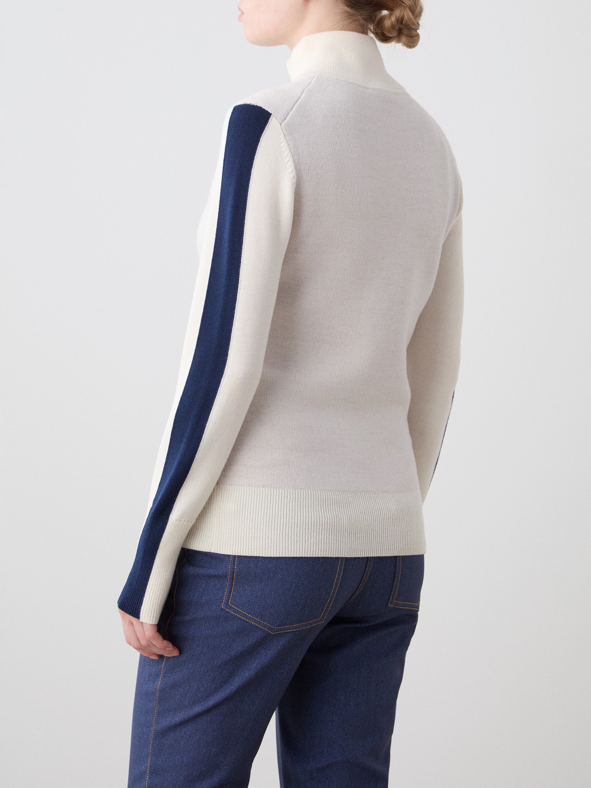 We Norwegians | FW25 | The model is wearing womens Afterski zip-up in cream which has the logo and 1/4th zipper in the front, against an off white background | Back view