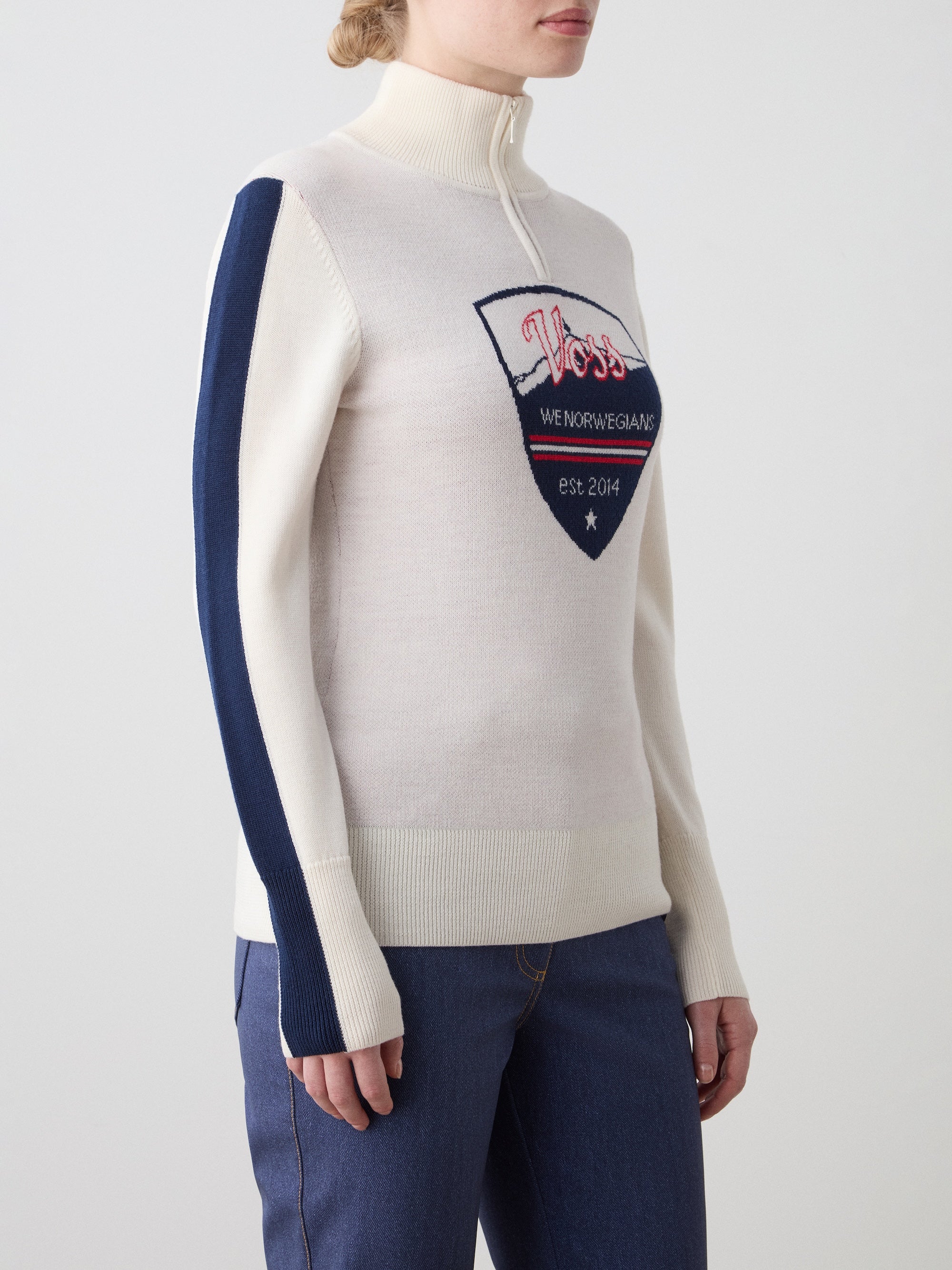 We Norwegians | FW25 | The model is wearing womens Afterski zip-up in cream which has the logo and 1/4th zipper in the front, against an off white background | Picture showing the details of the garment