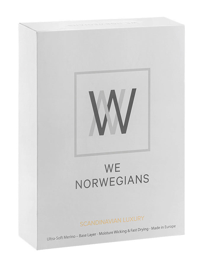 The product box is white and features the "We Norwegians" logo and text on the front. Underneath, it reads "Scandinavian Luxury Base-Layers," followed by details: "Ultra-Soft, Super Fine Merino Wool - Moisture Wicking & Fast Drying - Fitted Shape - Made in Europe." The box contains the Sno Merino Zip Up Women, a premium item by We Norwegians.